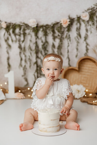 milestone child turning 1 with balloons during cake smash session in photography studio in petoskey