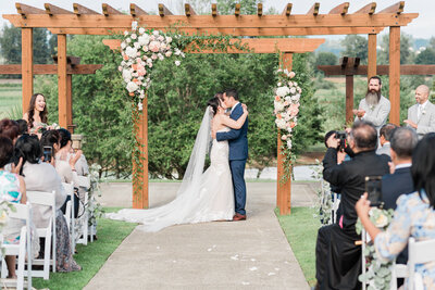 bride and groom posing in front of arbor at Lord Hills Farms  in Snohomish, Washington. This was captured  during their first kiss.