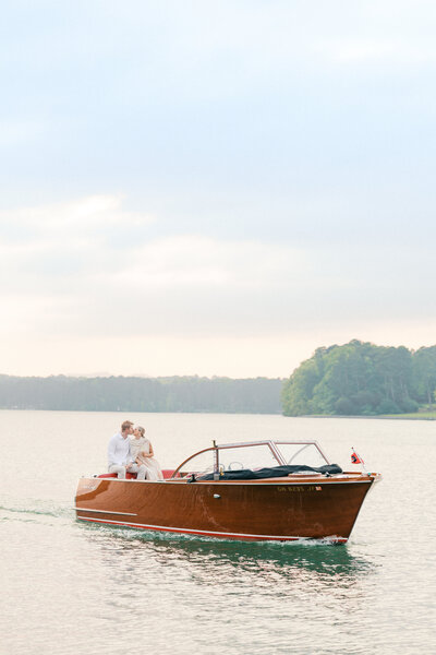 Bride and groom kiss on back of italian boat on Lake Lanier in Georgia