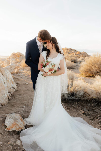 groom hugging bride from behind in sunset