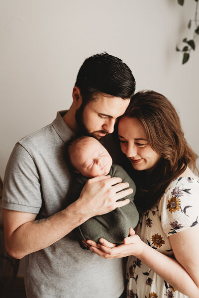 A couple holds tight to their newborn baby during a studio session at Nikii Pix Photography in downtown Bismarck. 