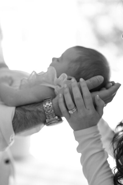 Couple hold their newborn in their hands during newborn session.