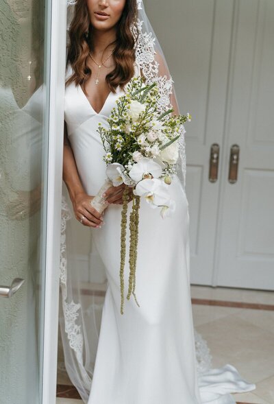 Bride leaning against door frame holding bouquet taken by east coast wedding photographer, Shelby Ann Photos