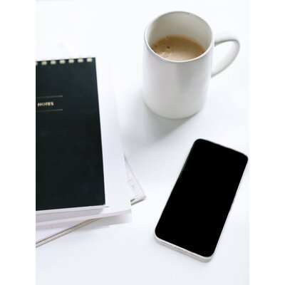white coffee cup with black notepad and iphone