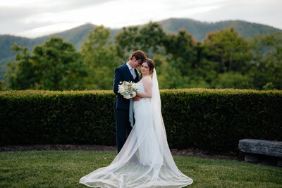 bride and groom smiling while embracing outside