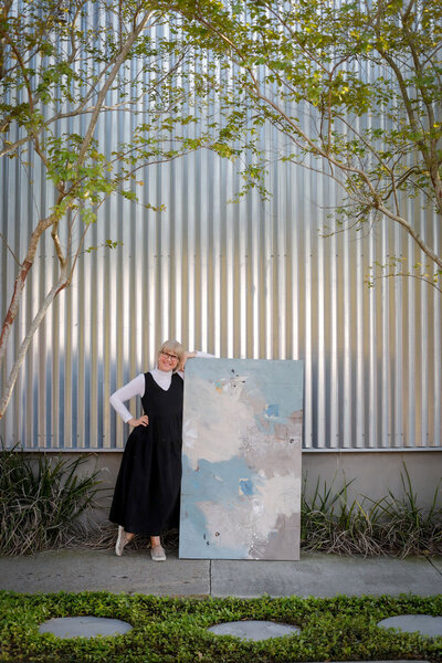 Adele on sidewalk carrying large abstract painting