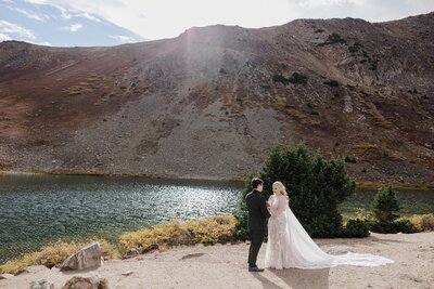 Bride and groom exchange private vows at Pass Lake on elopement day.