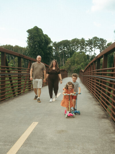 A family of four walk and ride scooters at Noonday Creek Trail-Towne Center in Georgia. 