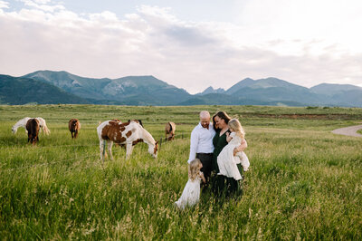 family in field with horses and mountains