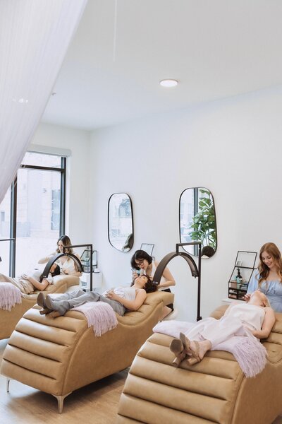 Three lash techs applying lash extensions to three Austin women laying on comfortable lash beds