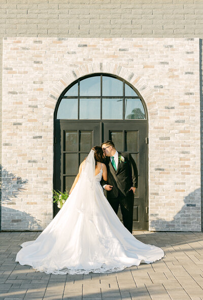 Elegant wedding session by a vintage car: The bride and groom stand close, gazing lovingly into each other's eyes, capturing a moment of timeless romance