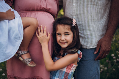 little girl smiling next to pregnant mother