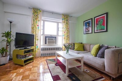 Stylish and modern apartment living room with hardwood floors, colorful accents, and comfortable furniture