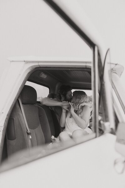 Couple kisses in the front seat of a pickup truck.