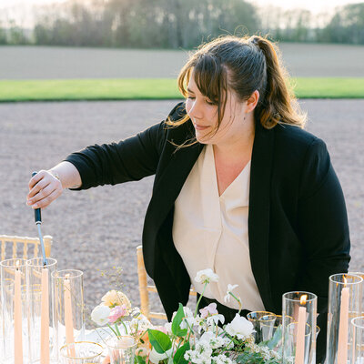 Wedding planner France en train d'allumer les bougies et terminer l'installation de la table de réception de mariage
