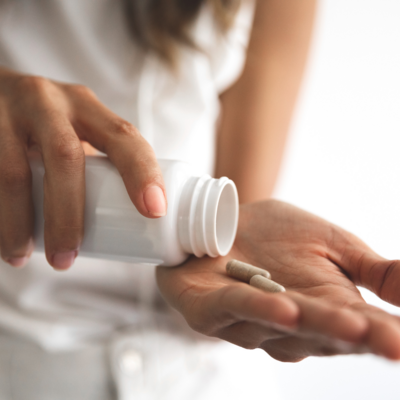 Person pouring supplements into hand, questioning the role of supplements in maintaining gut health