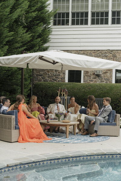 A group of friend talking beside the pool after wedding ceremony