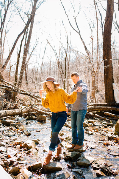 man and woman walking through  stream