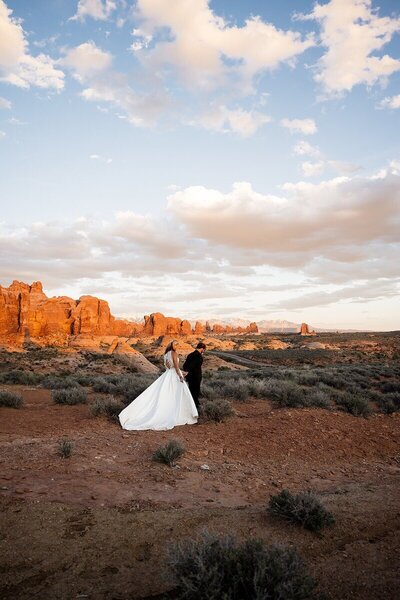 Couple overlooking the beautiful nature and landscape of moab with red dirt mountains.