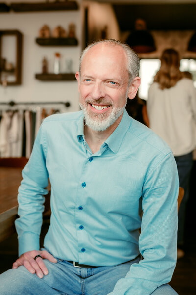After photo of man smiling in a professional dating profile portrait wearing a blue shirt, photographed in a Minneapolis studio setting