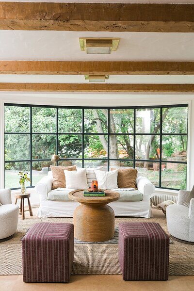 woman smiling and popping open champagne bottle, wearing a gold cardigan and a white t-shirt and a gold necklace