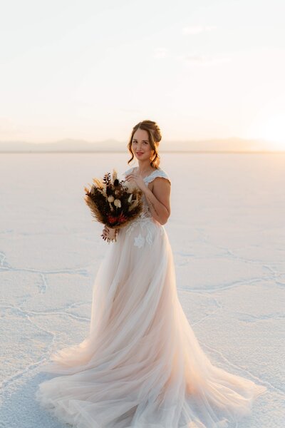 bride stands holding her bouquet on the bonneville salt flats