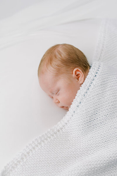  Richmond Newborn Photographer | Photo of a naturally-posed newborn baby boy with red hair sleeping on a white blanket by Jacqueline Aimee Portraits
