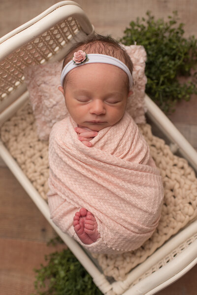 Baby girl wrapped in blush on white bed