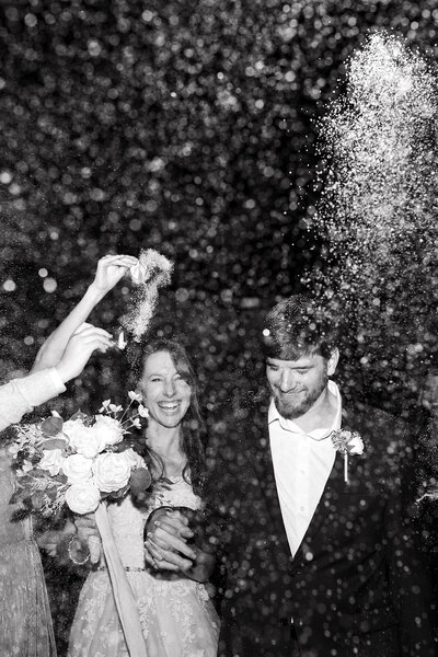 A newlywed couple gets confetti thrown at them from their guests