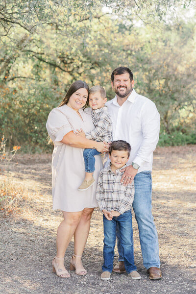 A family of 4 stand together at Brushy Creek Lake Park for their fall family session. 