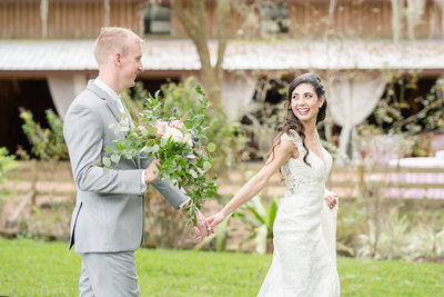 Bride holds grooms hand and leads him forward on wedding day