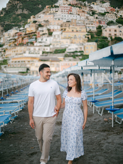 Engagement couple walking on the beach in Positano, captured by a luxury destination wedding photographer in Italy