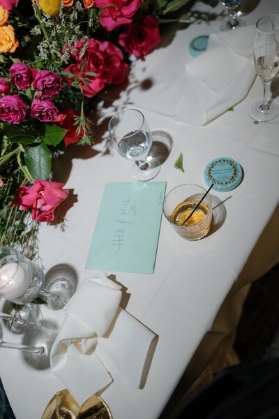 a letter for the bride and groom is left on their table at their wedding next to a whiskey glass and wedding favor caviar