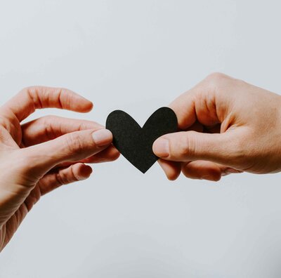 A couple holding a black paper heart, symbolizing love and emotional healing in life after divorce. This image reflects the complexities of post-divorce relationships, renewal, and the potential for finding love again.