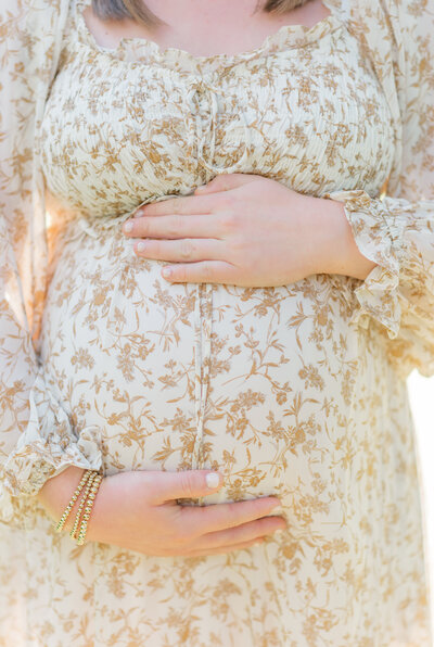 Light and airy maternity photo with mom-to-be holding her bump.