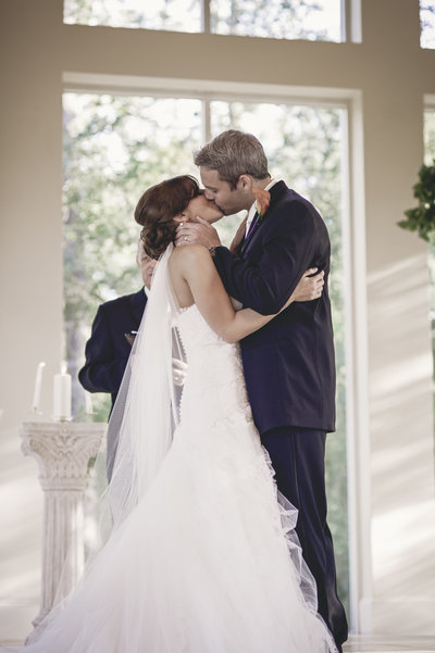 Capturing the bride and groom's first kiss in The Woodlands, TX by Sarah Farmer, a timeless wedding moment.