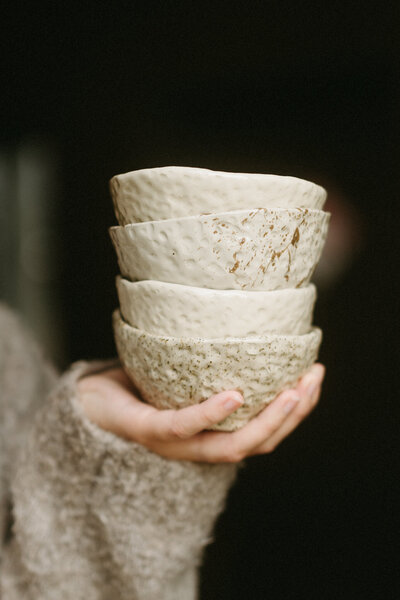 Hyllyllä on puinen pakki täynnä erilaisia siveltimiä ja työkaluja joita käytetään keramiikkatöitä tehdessä.