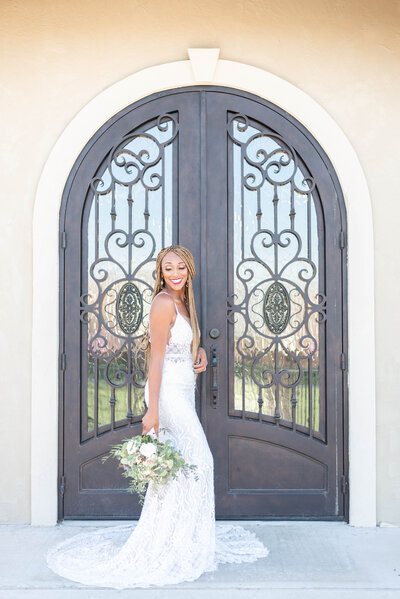 bride holding flowers at her side in front of iron doors