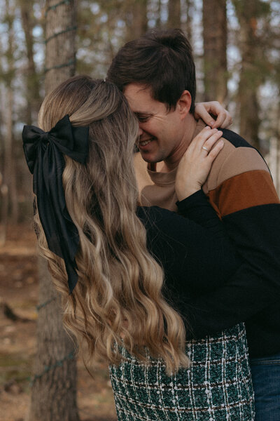 A couple poses forehead to forehead. The husband is smiling at his wife as her long hair sways back and forth.
