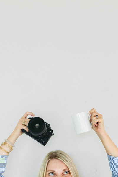 Natasha Sewell holding a camera and mug