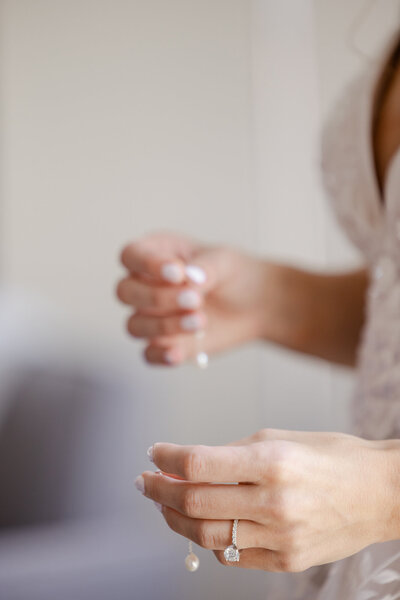 Bride holding her earrings on the wedding day