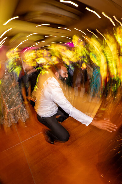 A person dancing at a wedding reception with blurred lights around them 