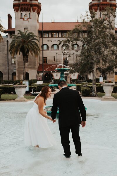 Couple walking into the Lightner Museum fountain to splash around at the end of their Saint Augustine elopement