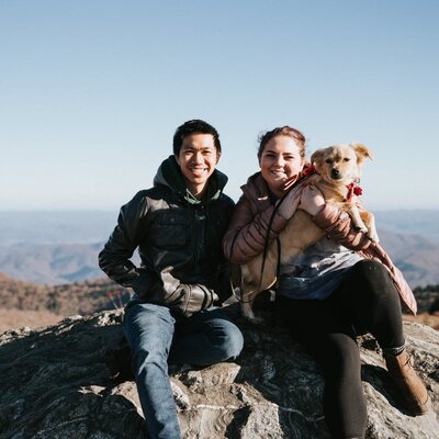 Shannon Lee, a Florida elopement photographer capturing a joyful moment of her and her husband, Eric, with their dog on a mountaintop.