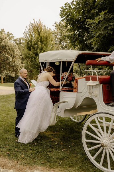 Bride and groom step into a horse-drawn carriage at their intimate rural wedding venue.