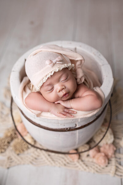 Newborn baby girl wrapped in tiffany blue fabric wearing a matching bow headband during her newborn photography session.