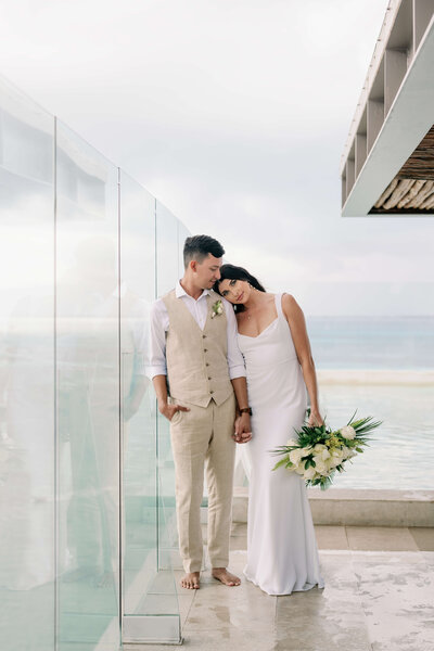 A Mexico wedding with the bride and groom posing for a photo in front of a glass wall.