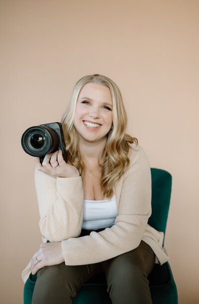 Photographer Janalee sitting in a chair in a studio with a camera in her hand