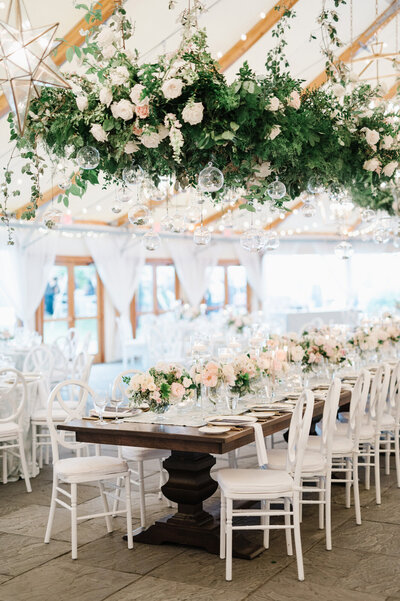 tented wedding reception table with a large floral decoration over it