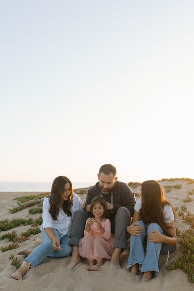 family of 4 sitting on beach
